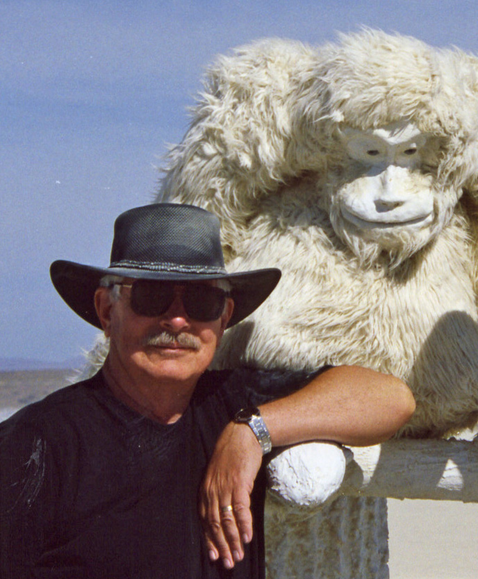 I made my first journey to Burning Man in 2003. This photo is taken from 2006 when I posed next to a great ape in an evolution sculpture. Playa dust decorates my hat and T-shirt.